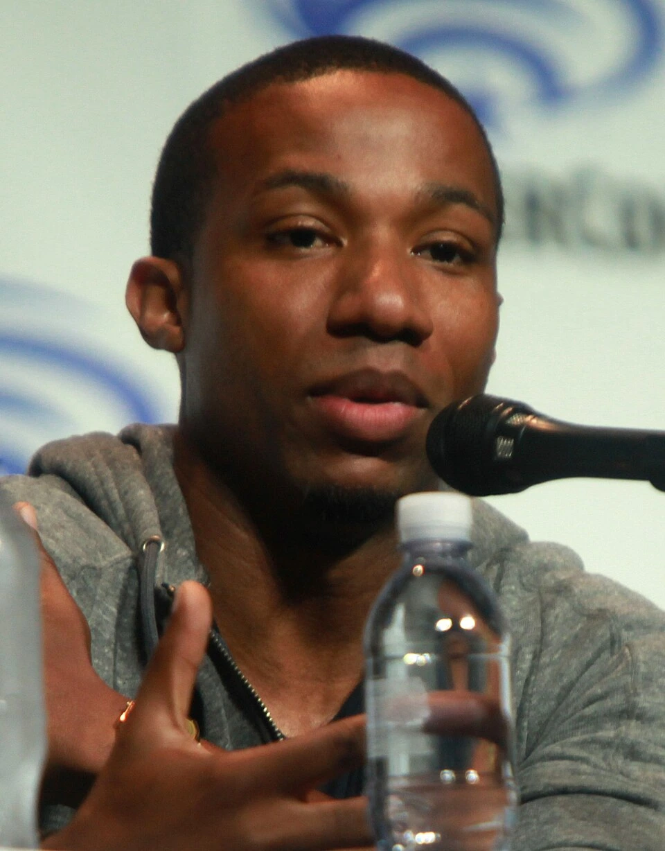 Arlen Escarpeta speaking at a microphone during a panel appearance